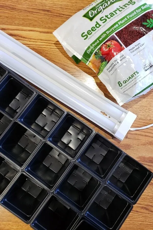 supplies needed for starting seeds indoors include trays, led shop lights, seed starting soil, and a way to hang the lights. 