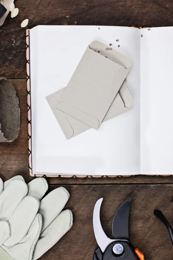 A garden journal sitting on a table with gloves, clippers, and seed packets