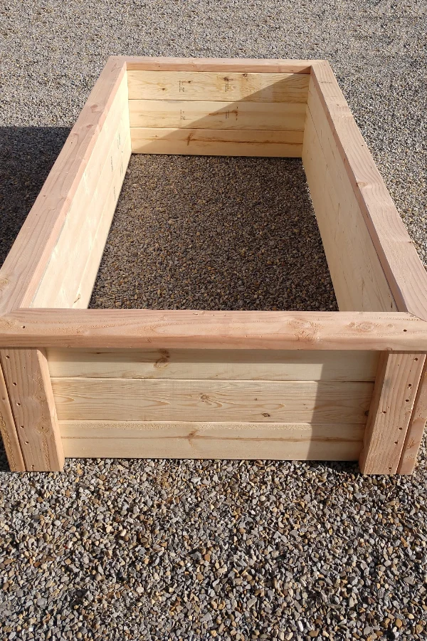 An empty raised bed sitting on rocks