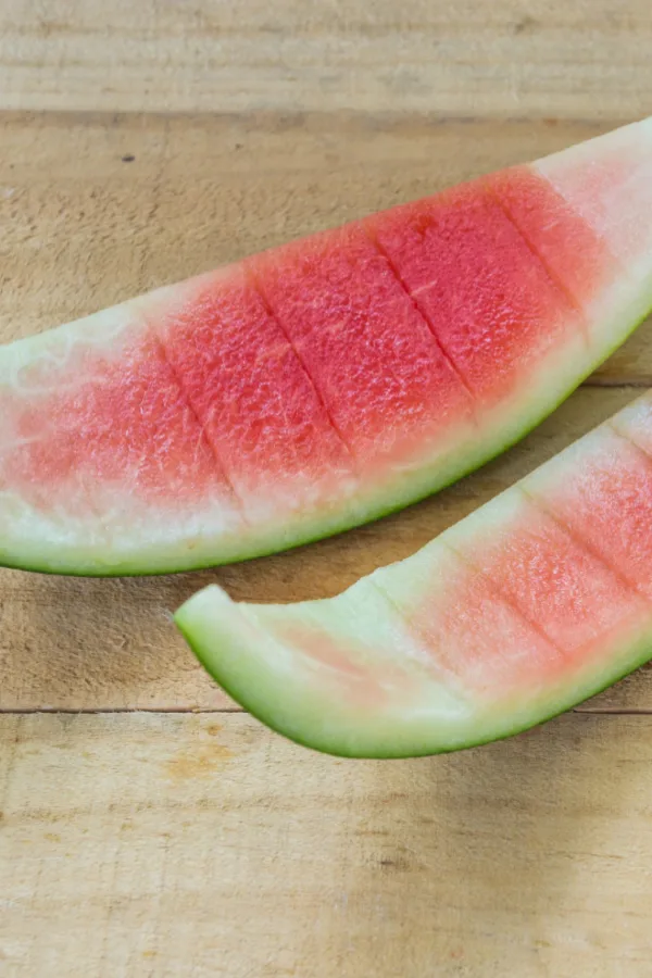 two empty watermelon rinds on a wooden table. 