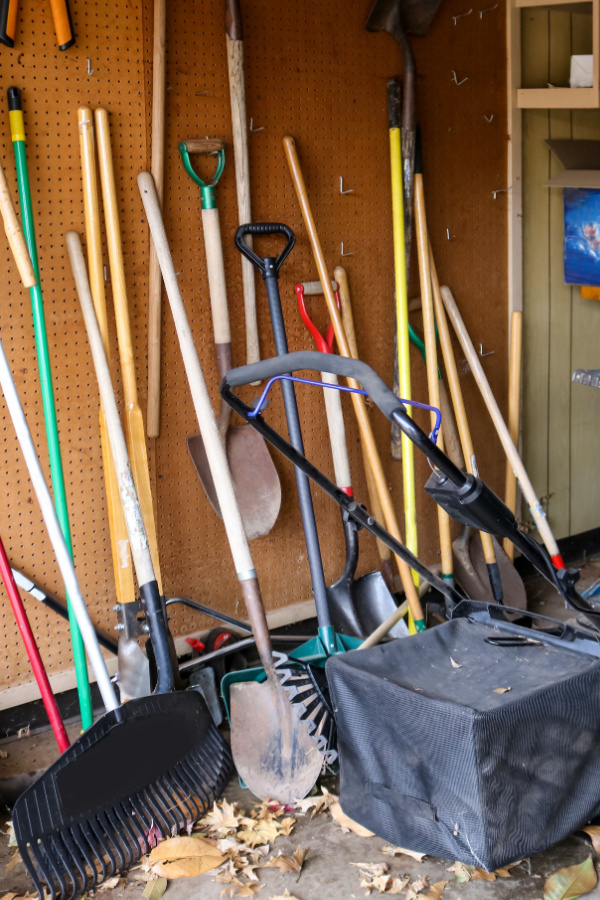 A messy garage with tools leaning and resting everywhere. 