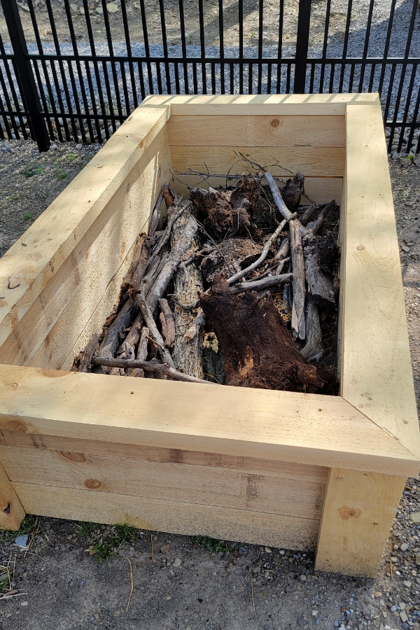Adding bark and wood to the first layer of raised beds