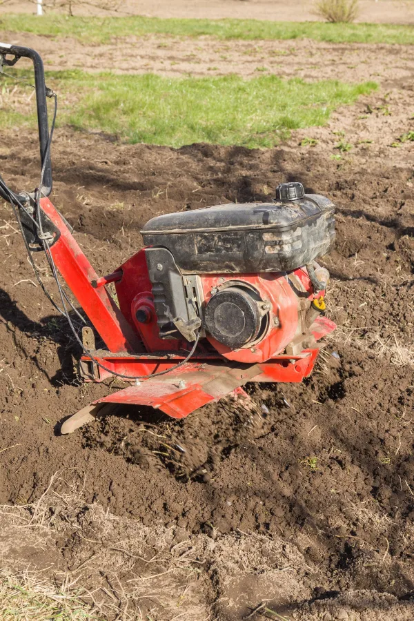 A red rototiller working the garden soil.