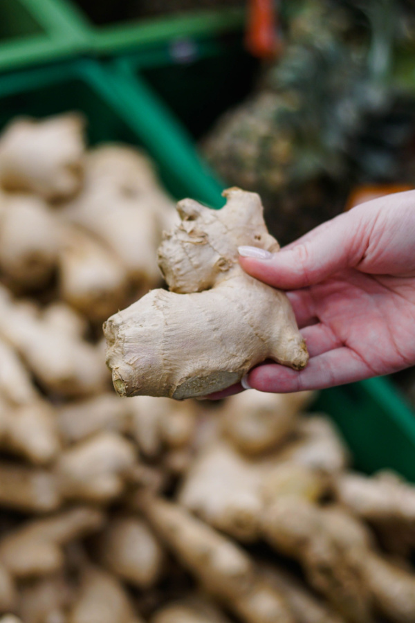 A hand holding a piece of ginger root at a store. 