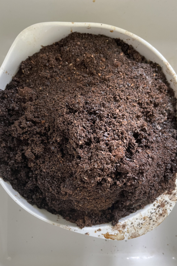 A white bowl of used coffee grounds.